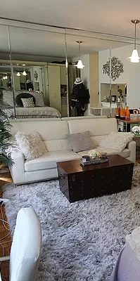 Part of the living room of 161 West 61st Street Apt 9D, showing the sofa, carpeting, and a mirror on the background.